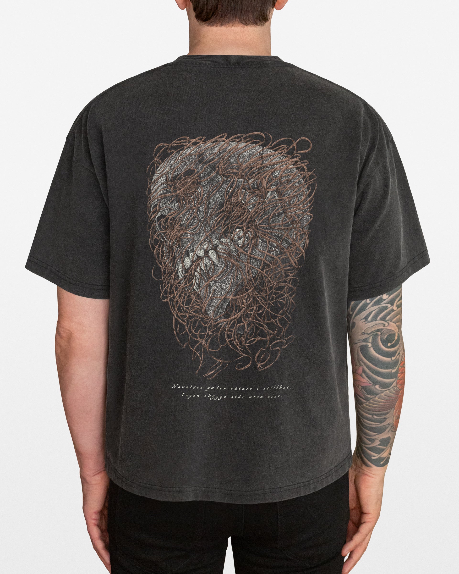 A dark gray acid wash oversized t-shirt with a distressed skull design on the back, worn by a person.
