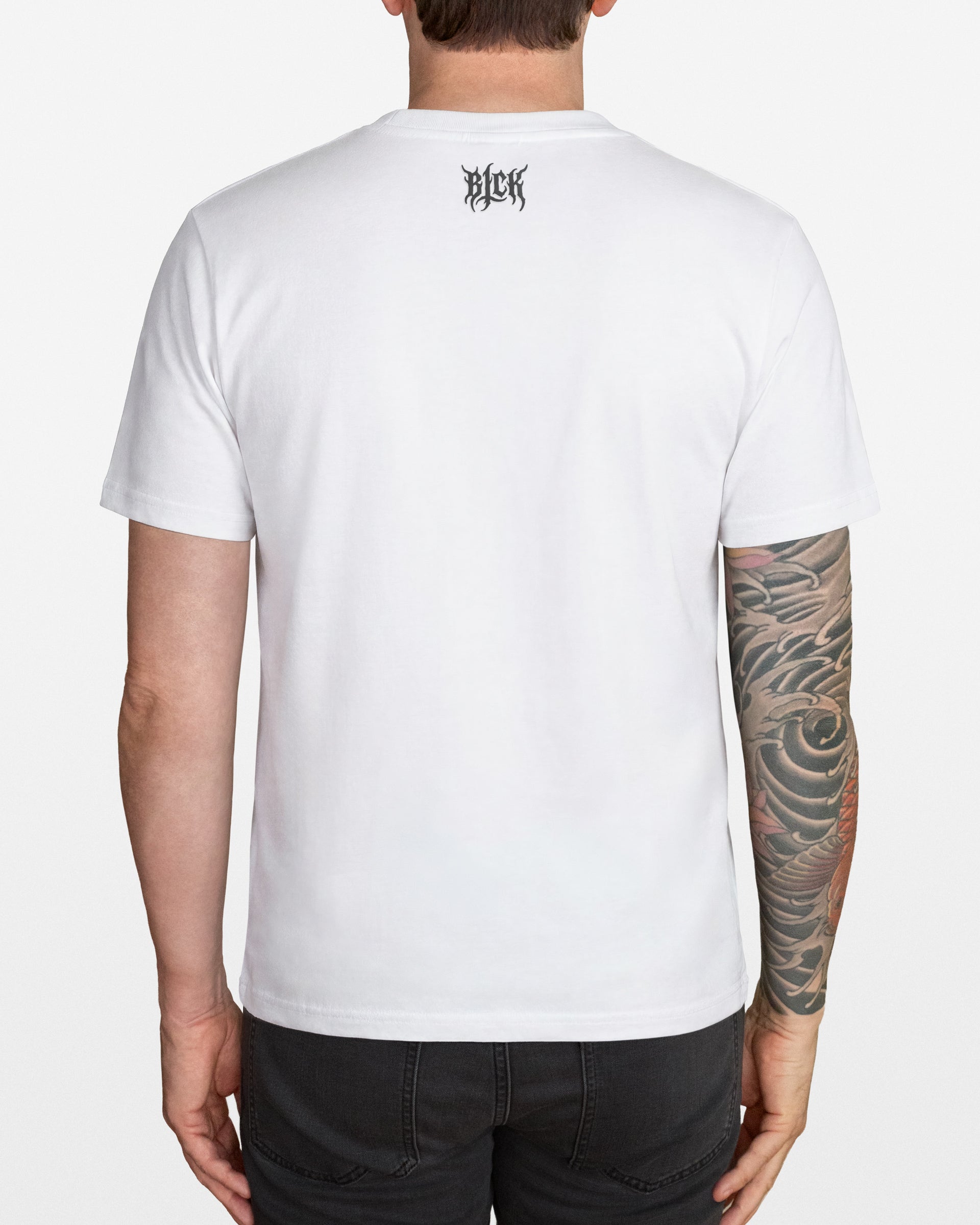 Person wearing a white t-shirt with a small logo on the back neck, standing against a plain background.