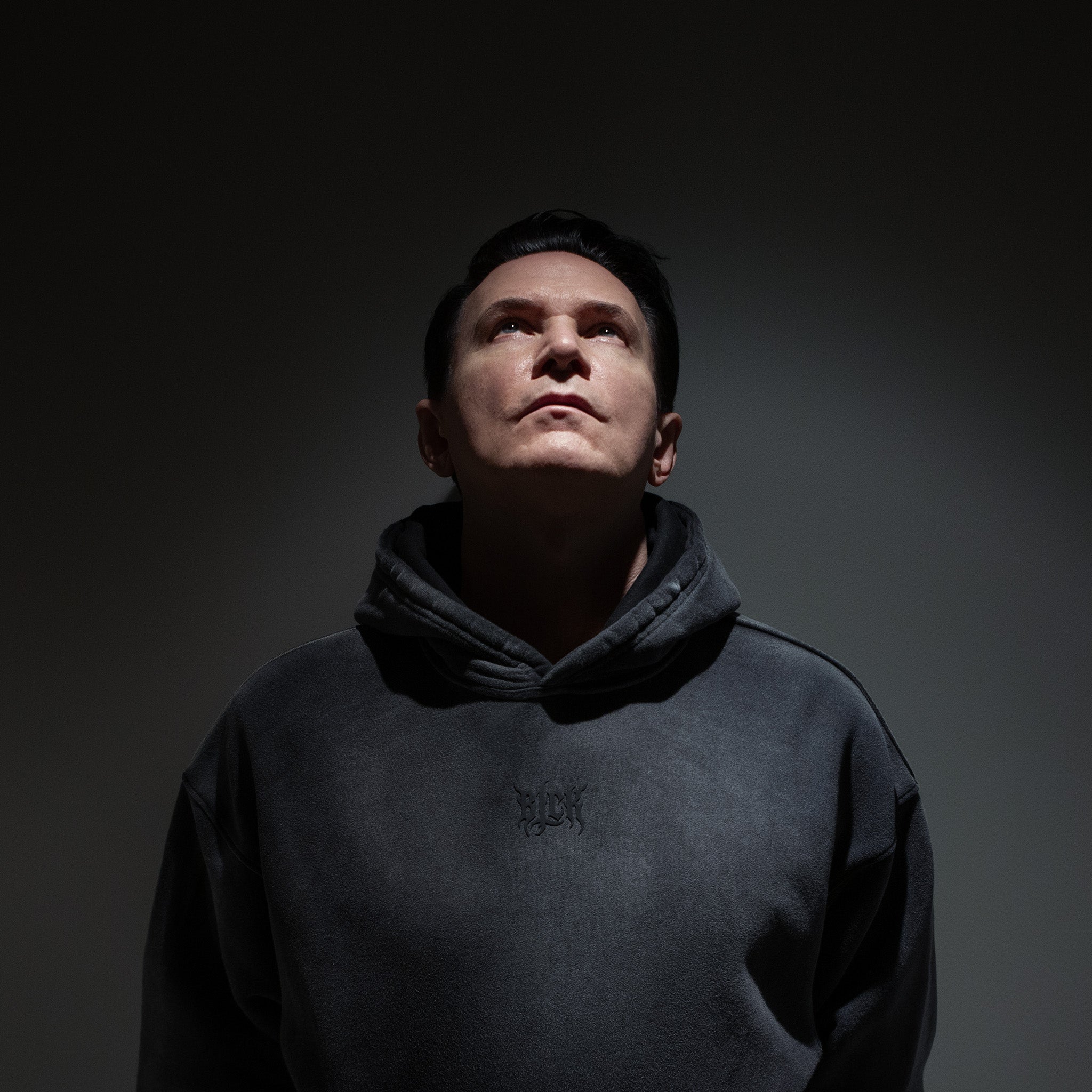 Person wearing a dark hoodie against a black background