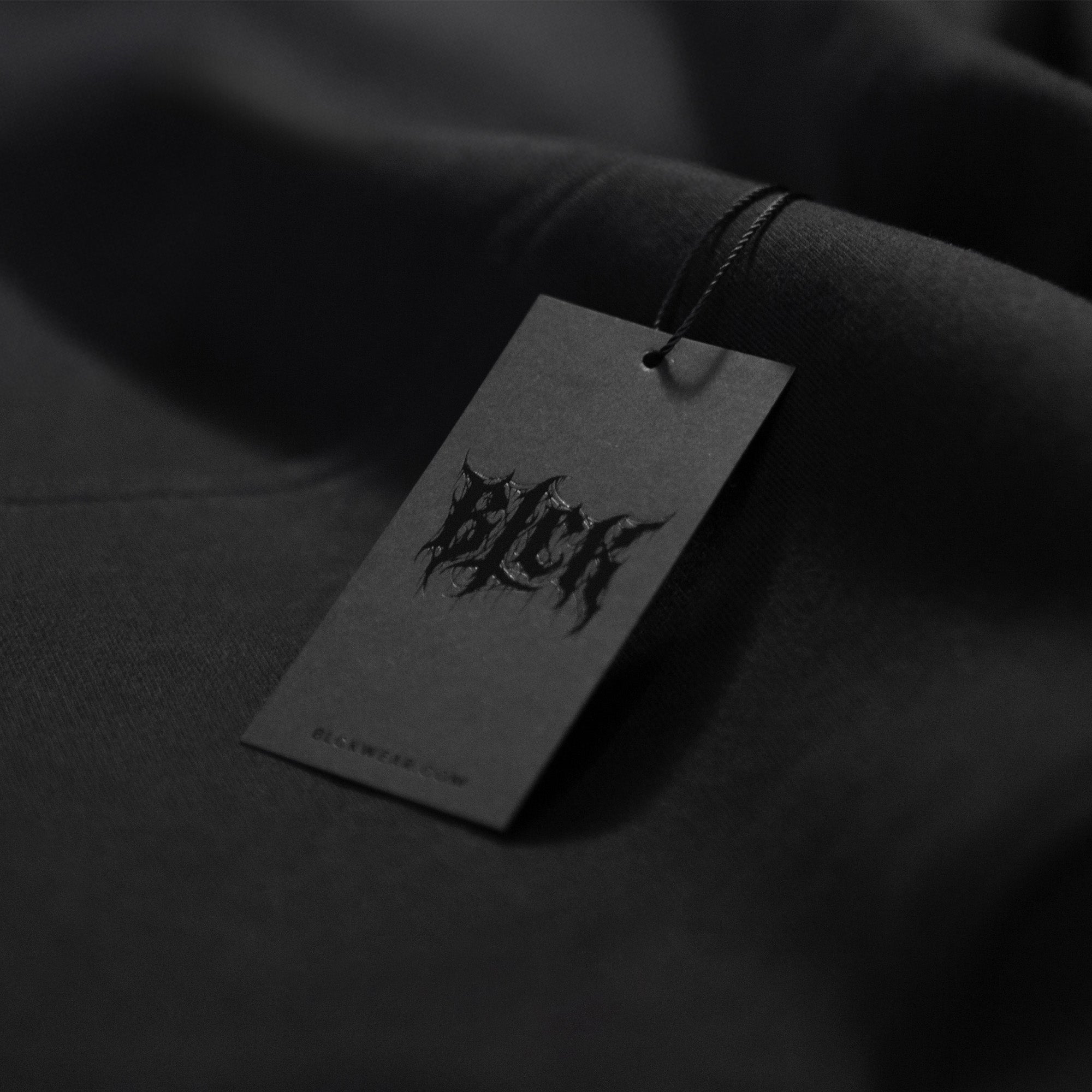 Black hang tag label on a dark fabric background