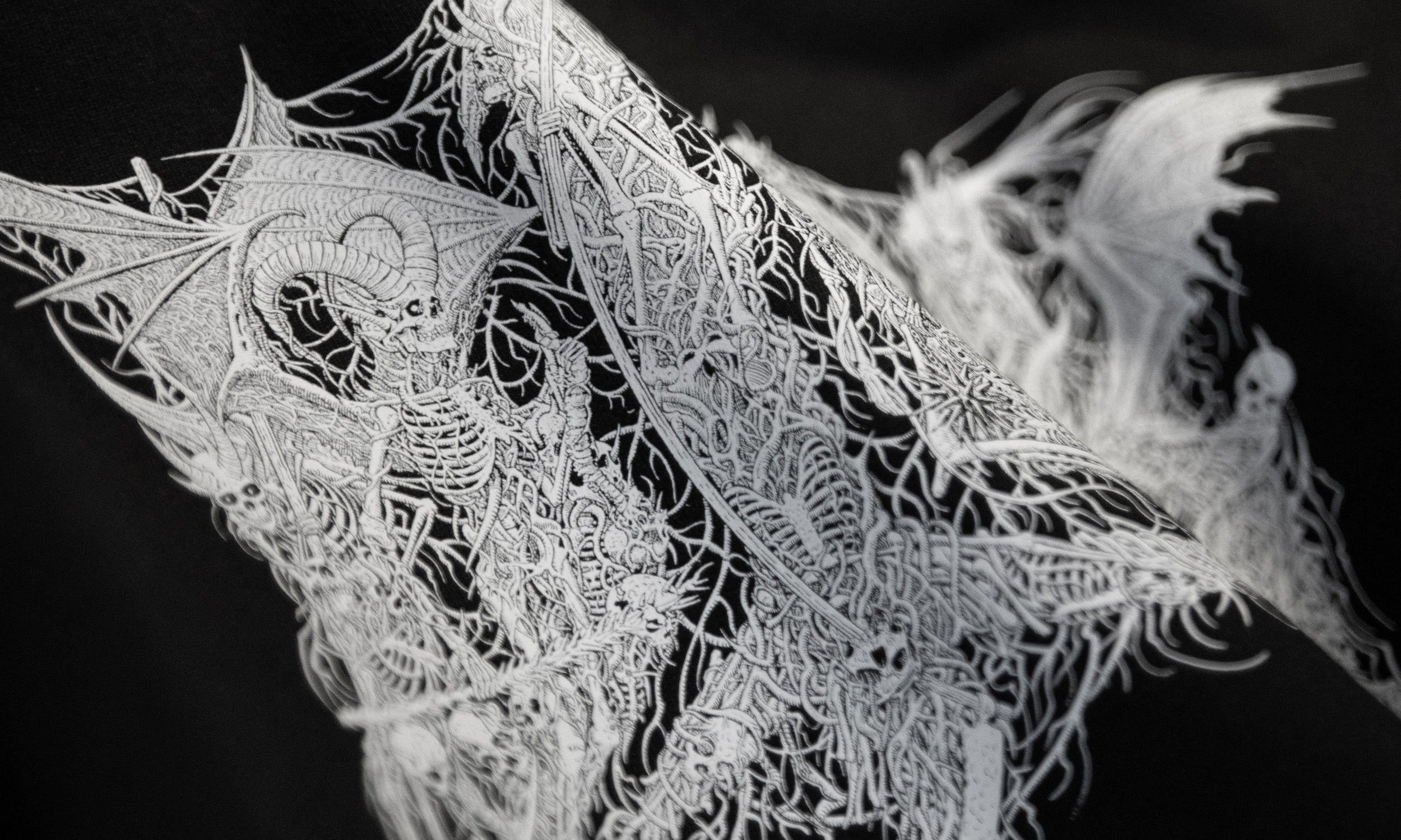 Close-up of a detailed black and white occult skeletons illustration printed on fabric.