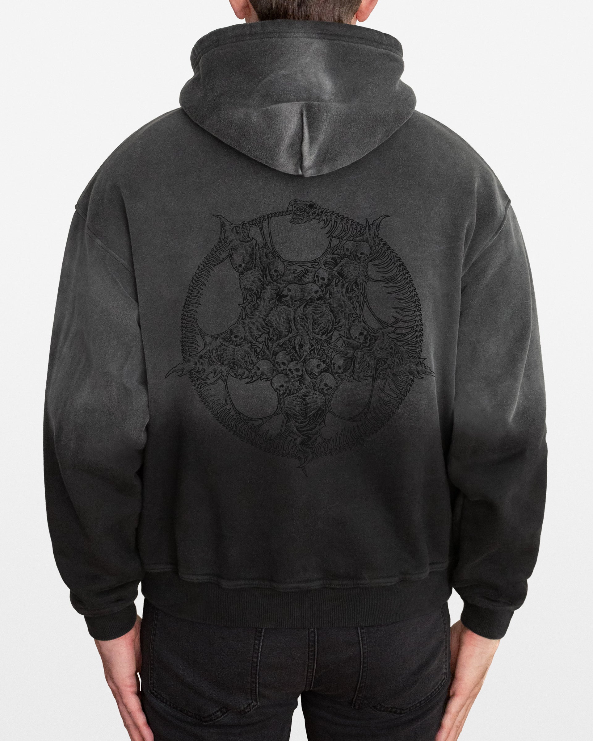 Person wearing a dark gray sun faded hoodie with a detailed black pentagram skulls design on the back, on a white background