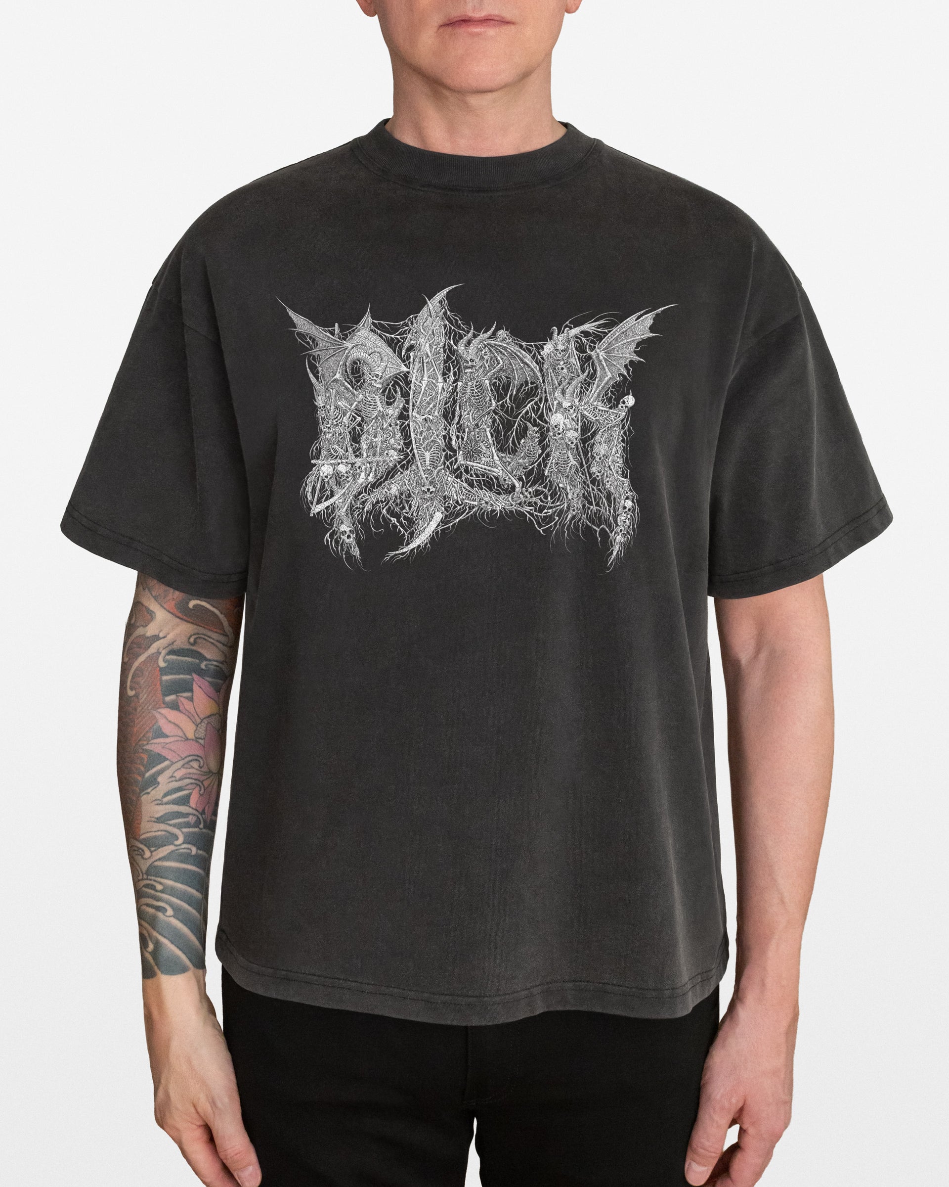 Person wearing a dark gray acid wash oversized t-shirt with an intricate BLCK logo skeletons design, on a white background