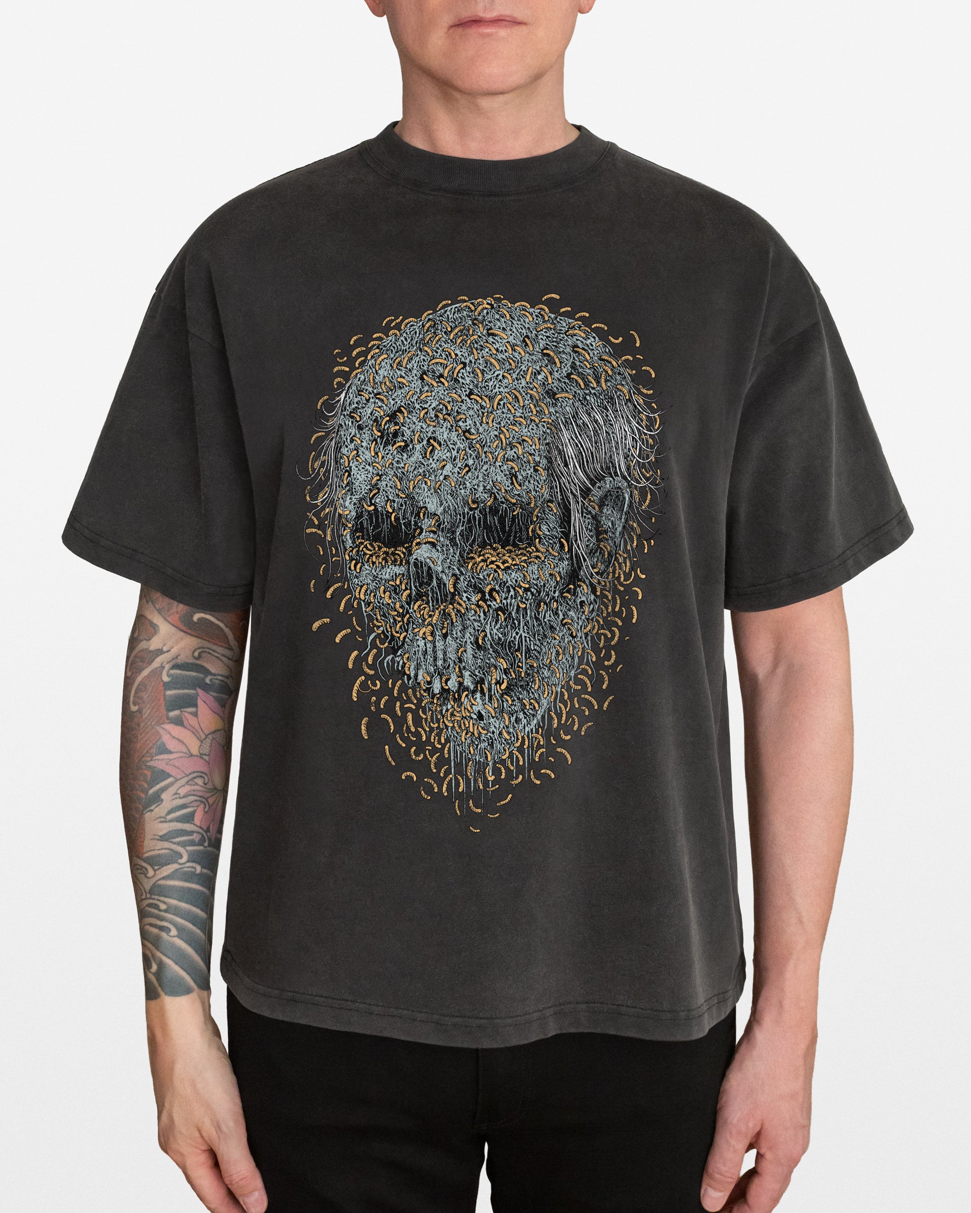 Person wearing a dark gray acid wash oversized t-shirt with a maggot skull design, on a white background